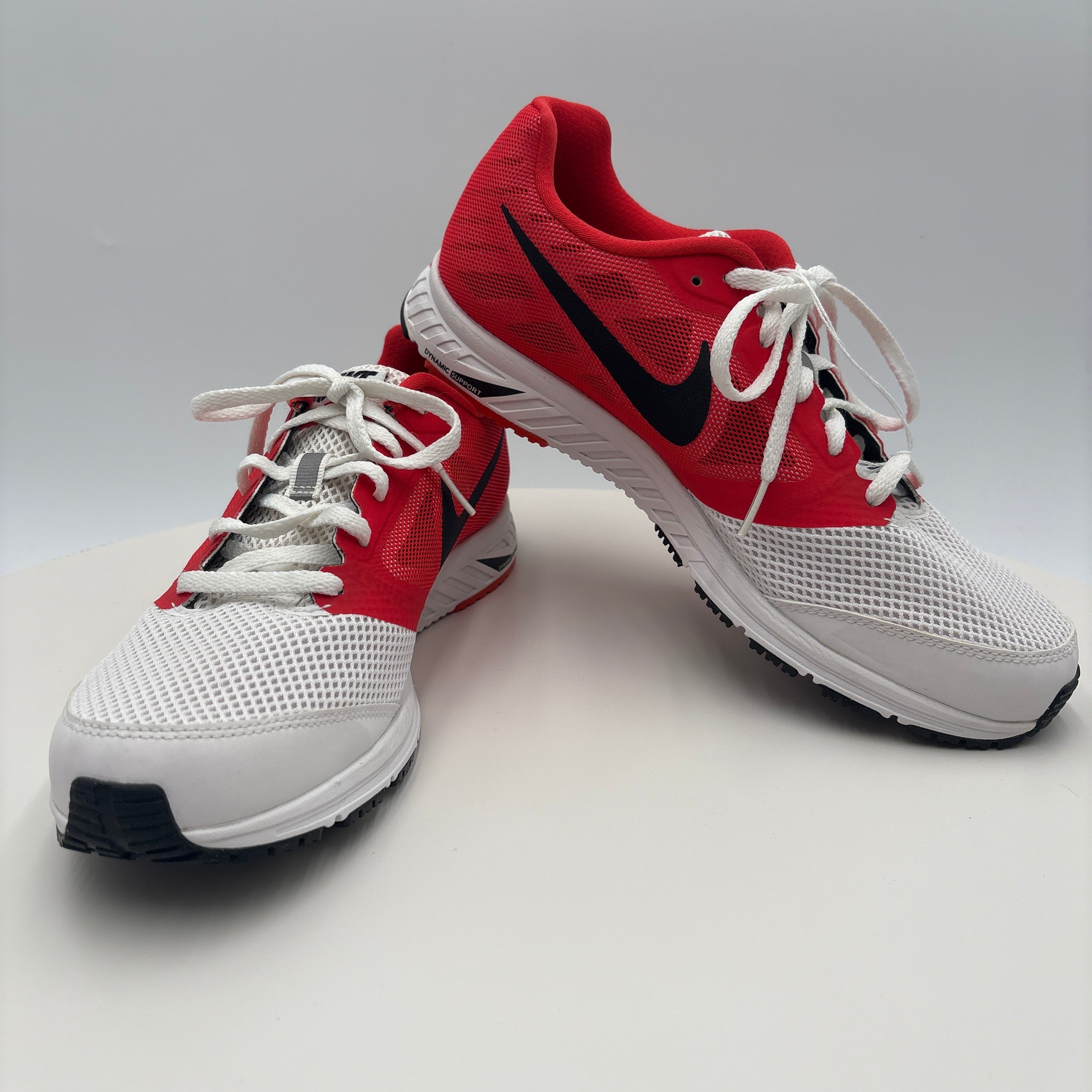 Red and white athletic shoes with black accents on a light gray background