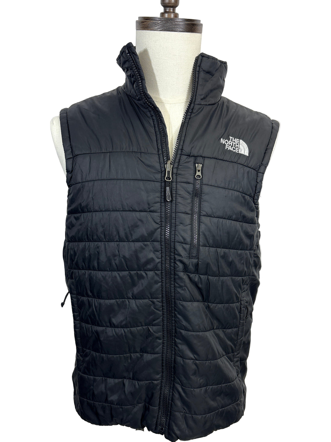Black quilted jacket on a mannequin against a white background