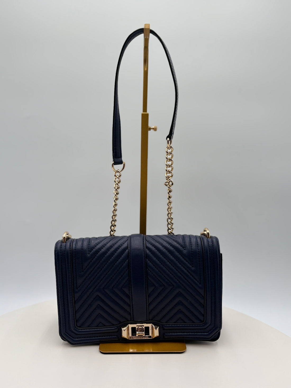 Navy blue handbag with gold accents on a white background
