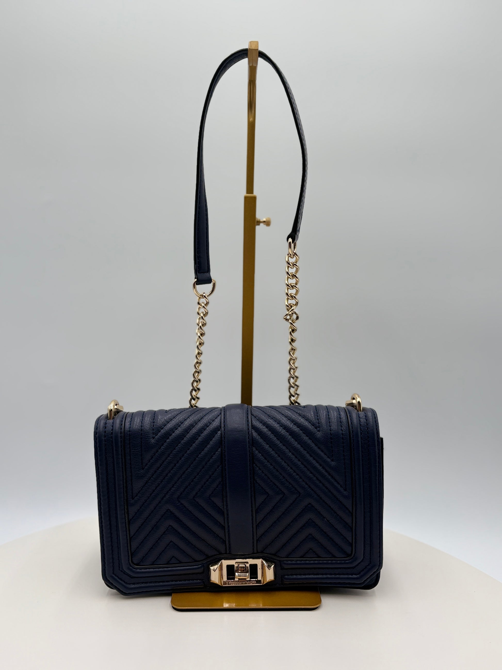 Navy blue handbag with gold accents on a white background