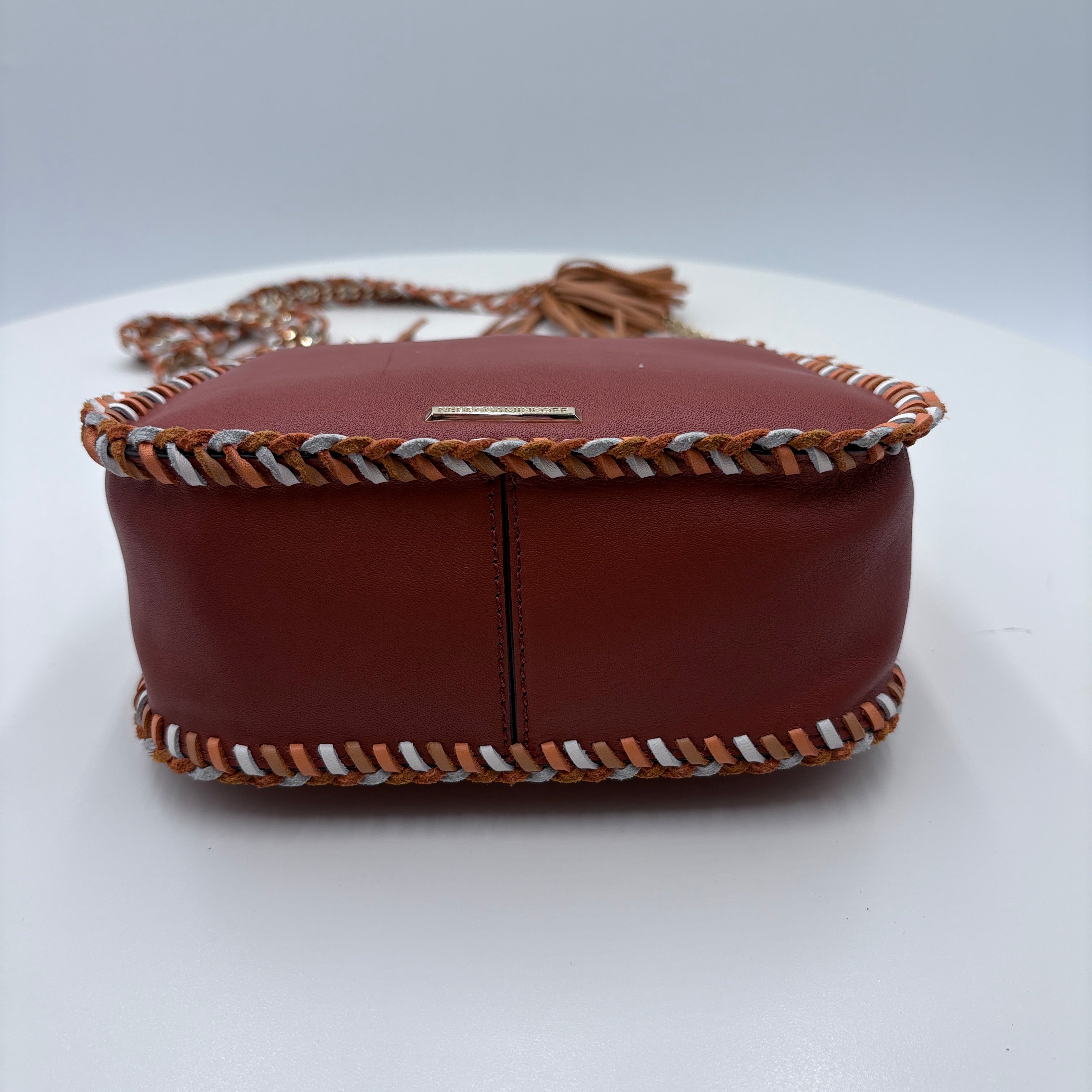 Brown leather handbag with decorative strap on a white background