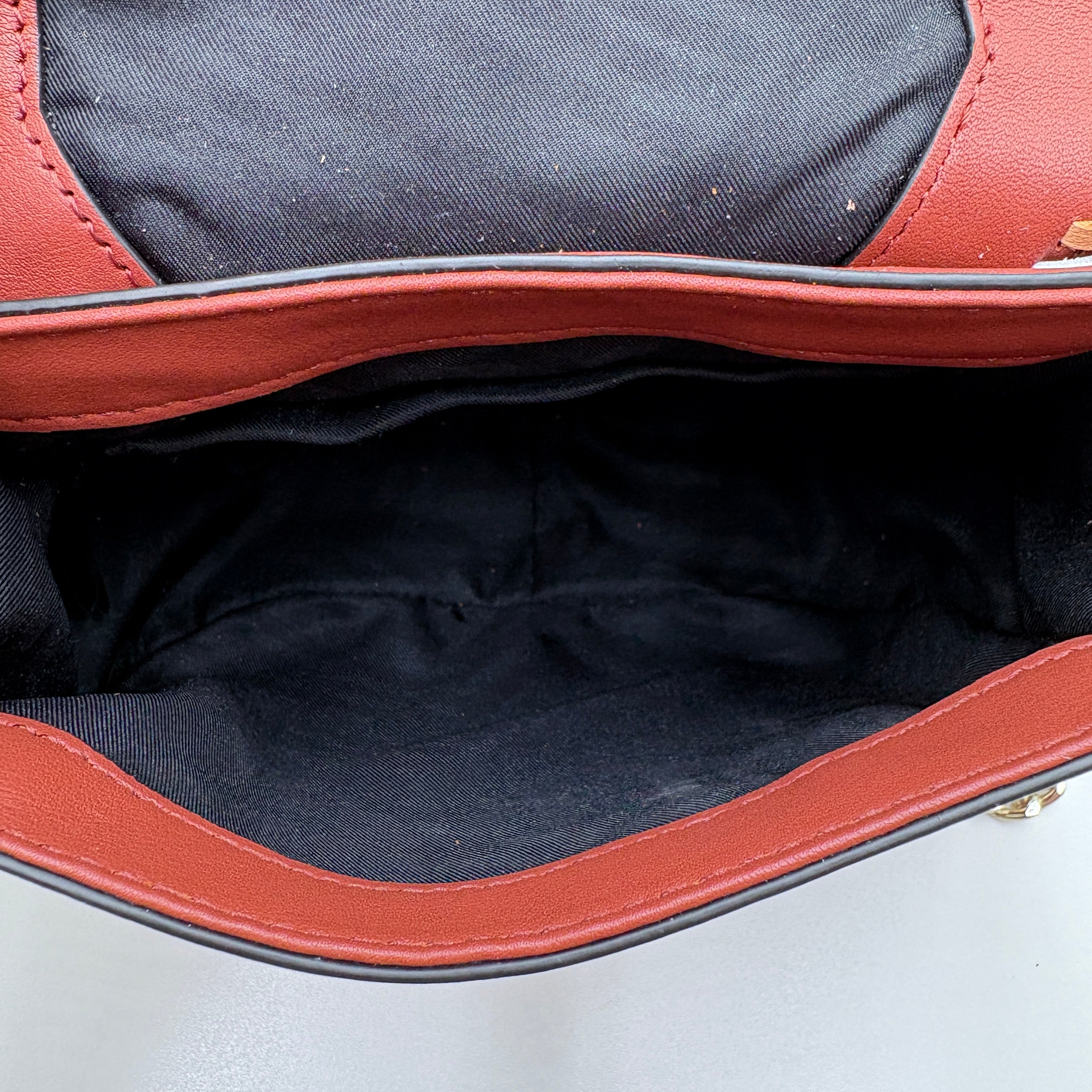 Close-up of a brown leather bag with black interior lining on a light gray background