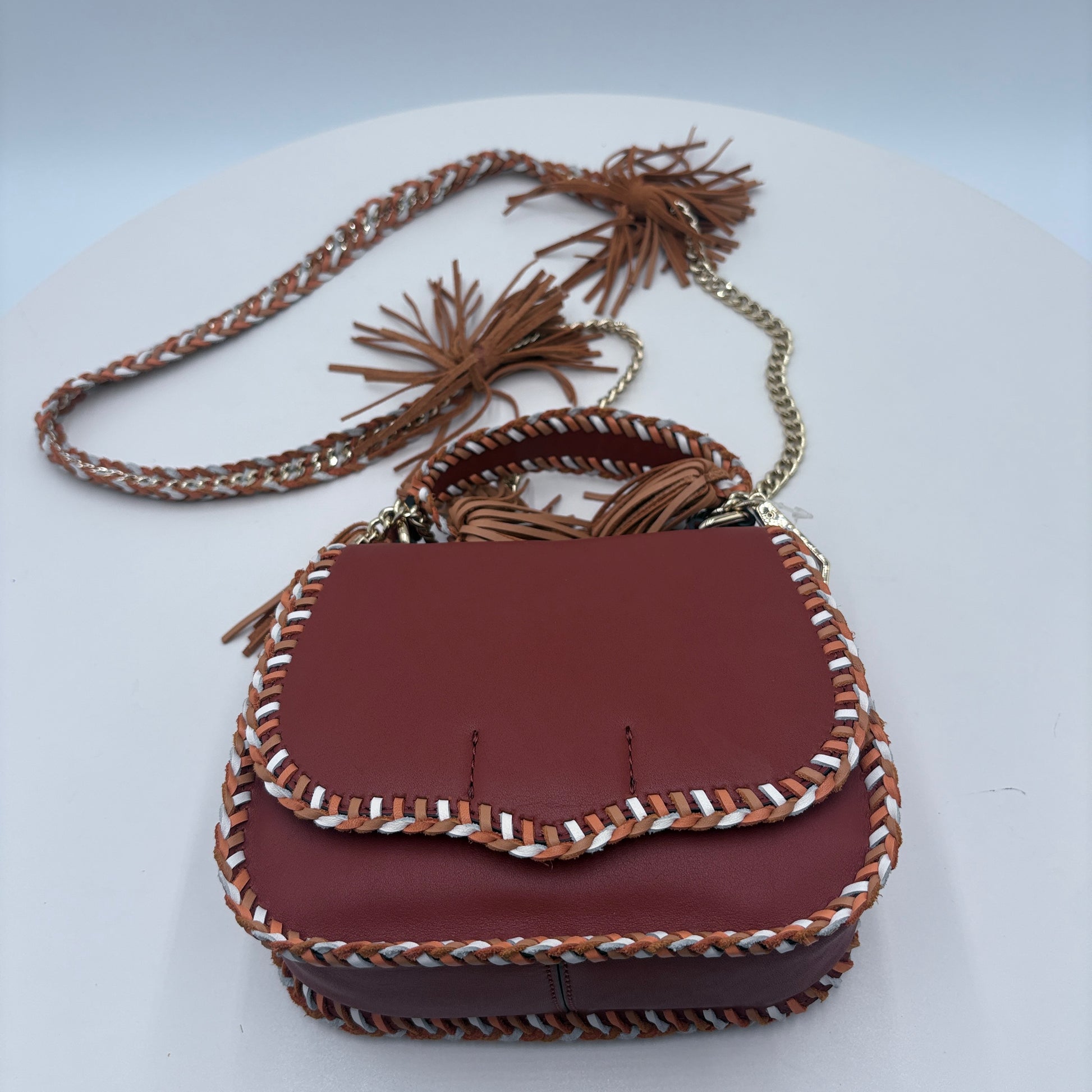 Brown leather handbag with braided details on a white background