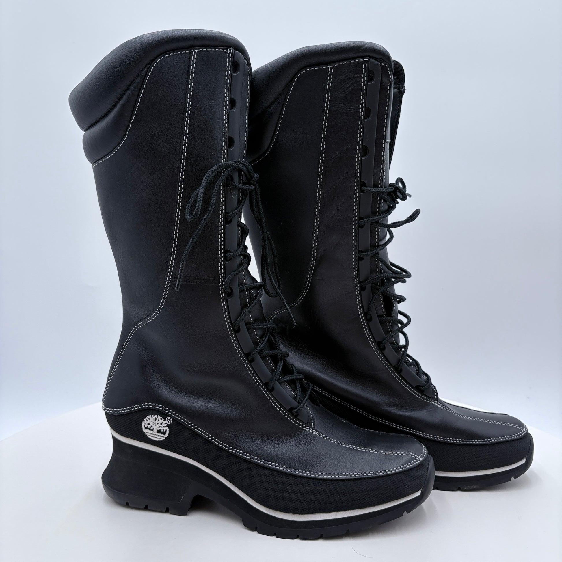 Pair of black boots with a visible brand logo on a light gray background