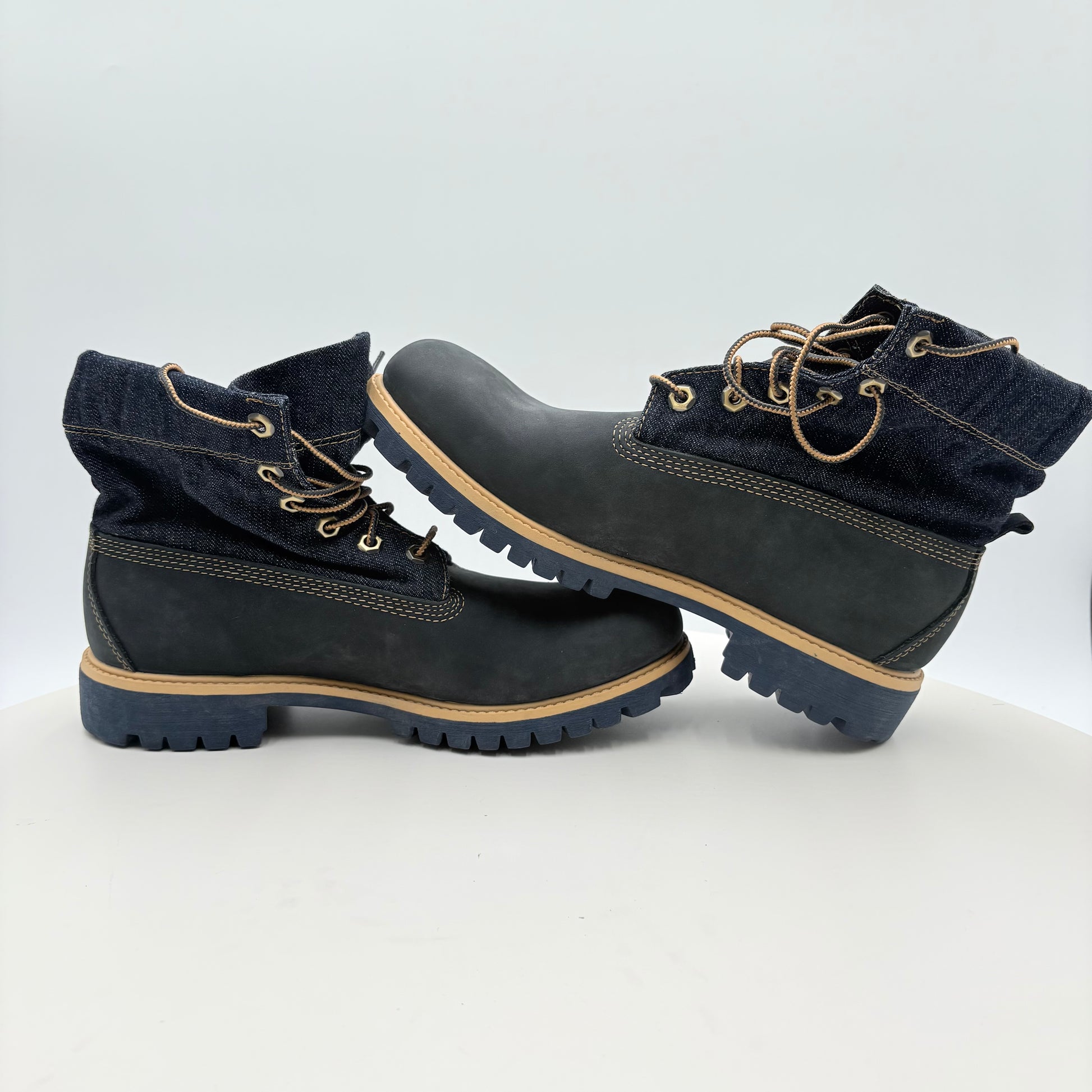 Pair of black boots with beige laces and soles on a white background