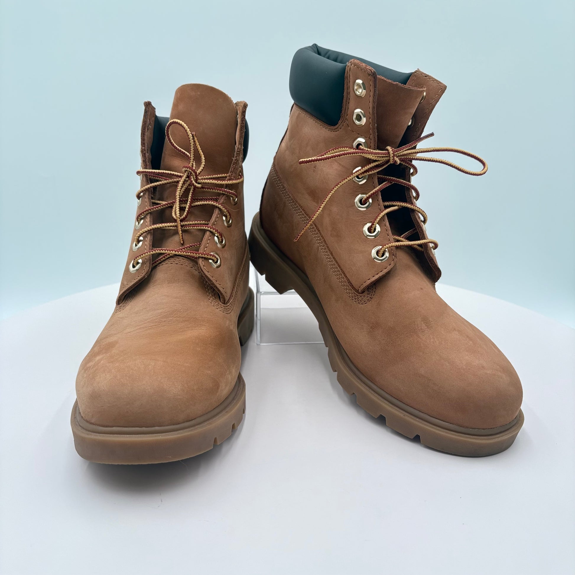 Pair of brown leather boots on a white platform with a light blue background