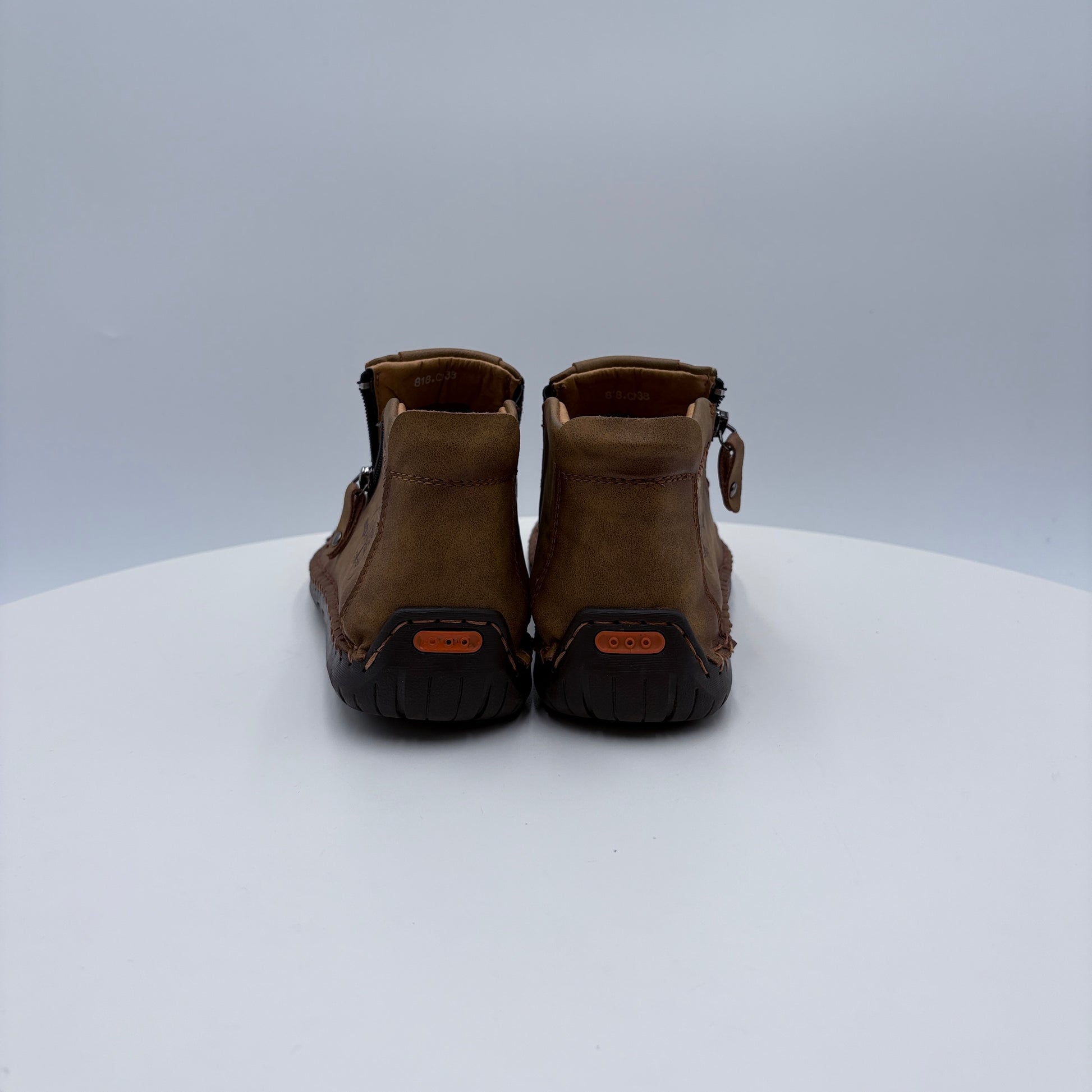Pair of brown moccasins on a white platform with a light gray background