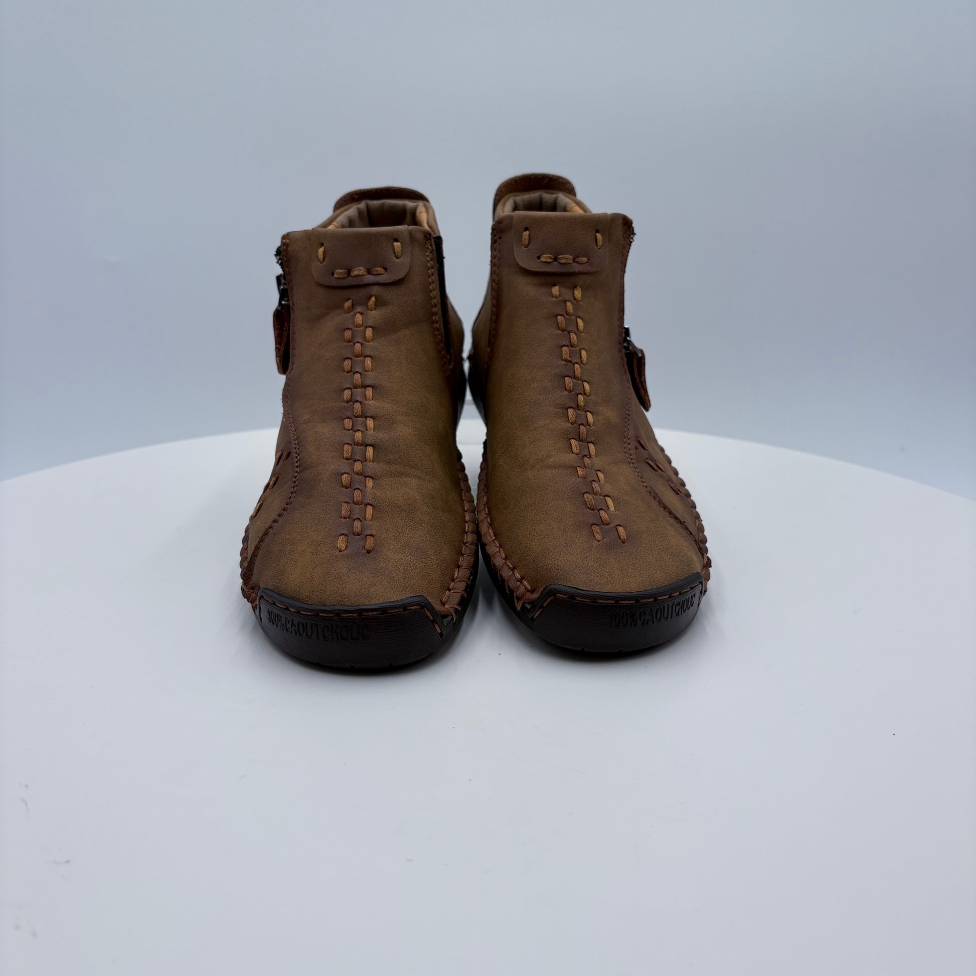 Pair of brown leather mocassins on a white platform with a light gray background