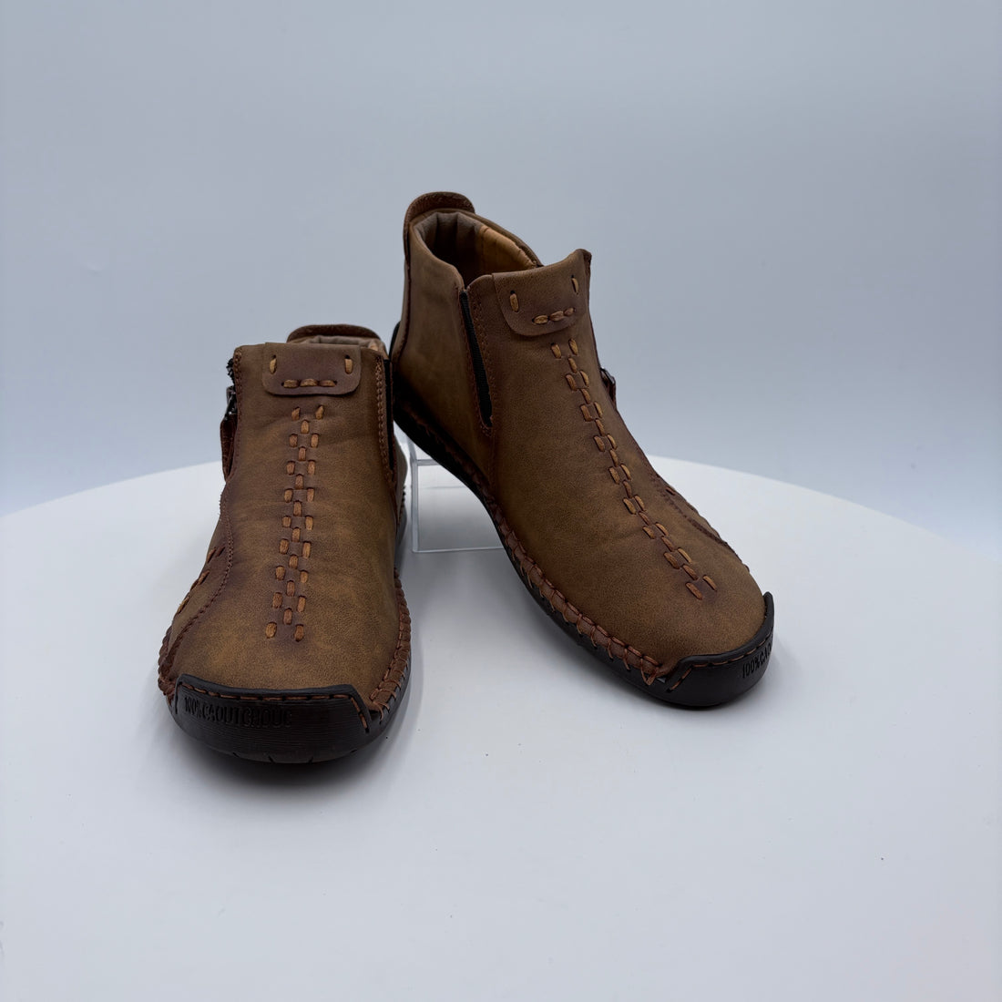 Pair of brown leather moccasins on a white platform with a light gray background