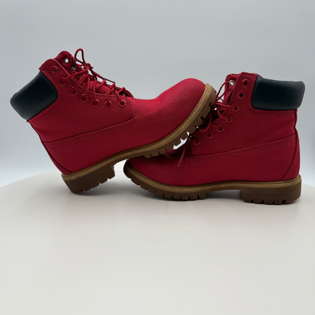 Pair of red boots with black soles on a light gray background