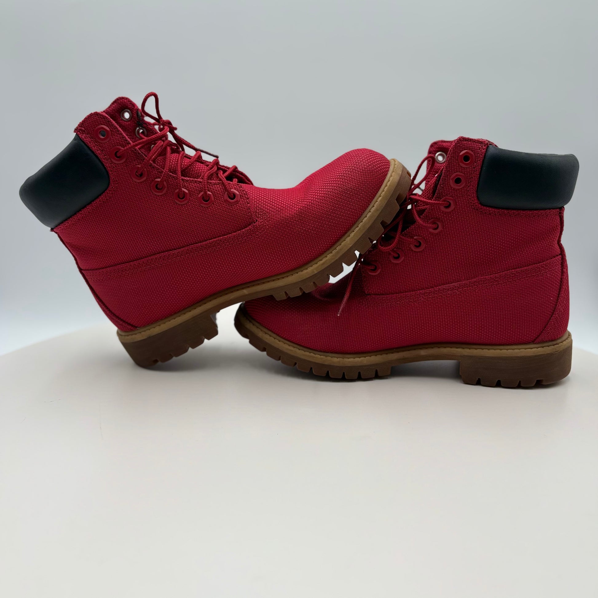 Pair of red boots with black soles on a light gray background