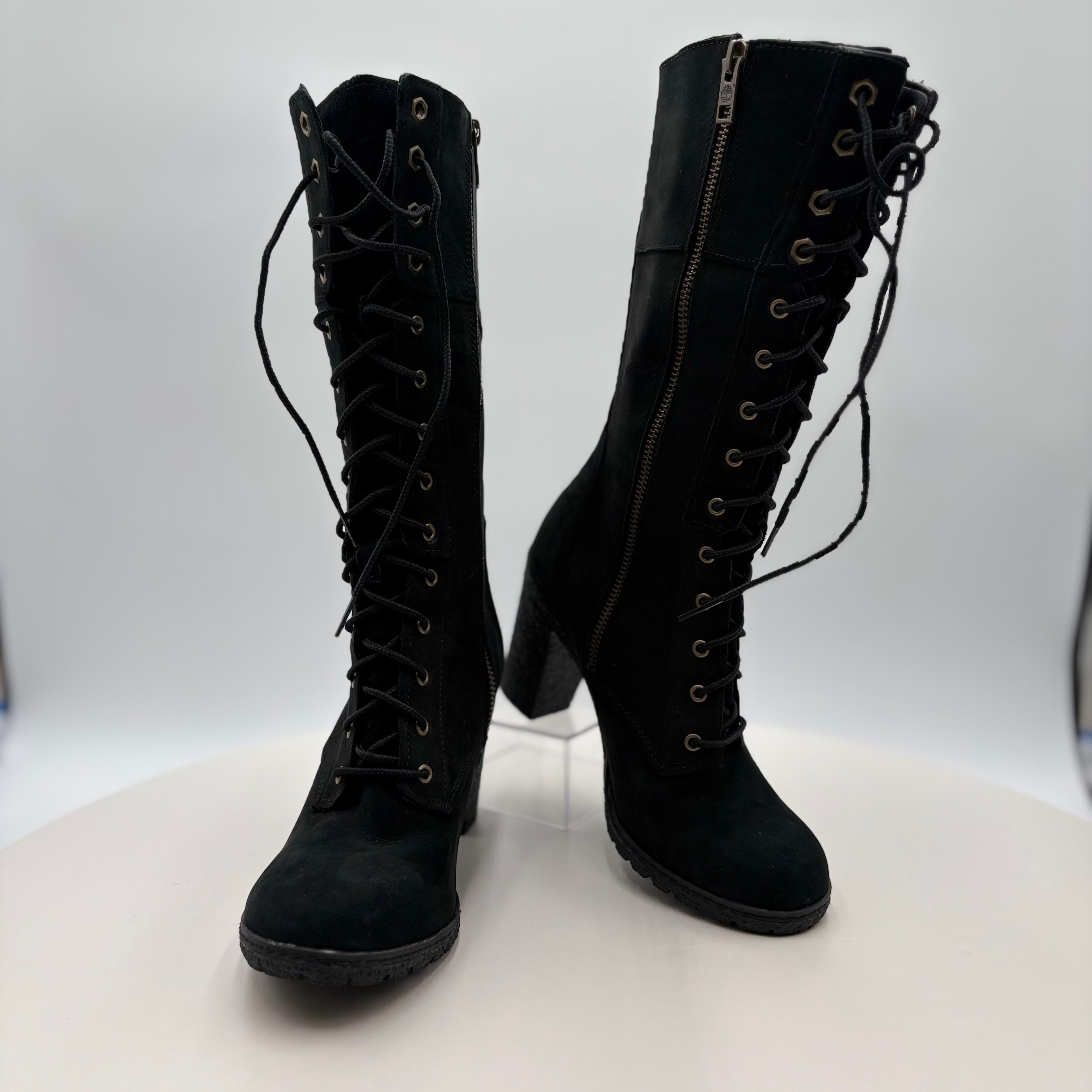 Pair of black knee-high boots with laces and a zipper on a white background