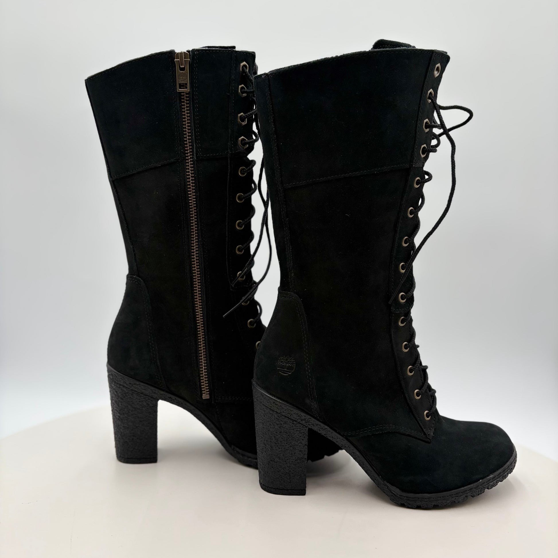 Black suede boots with lace-up design on a white background