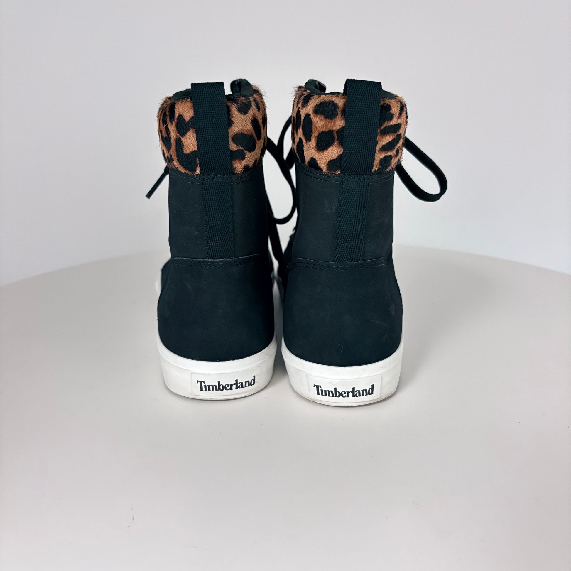 Black high-top sneakers with leopard print accents on a white background