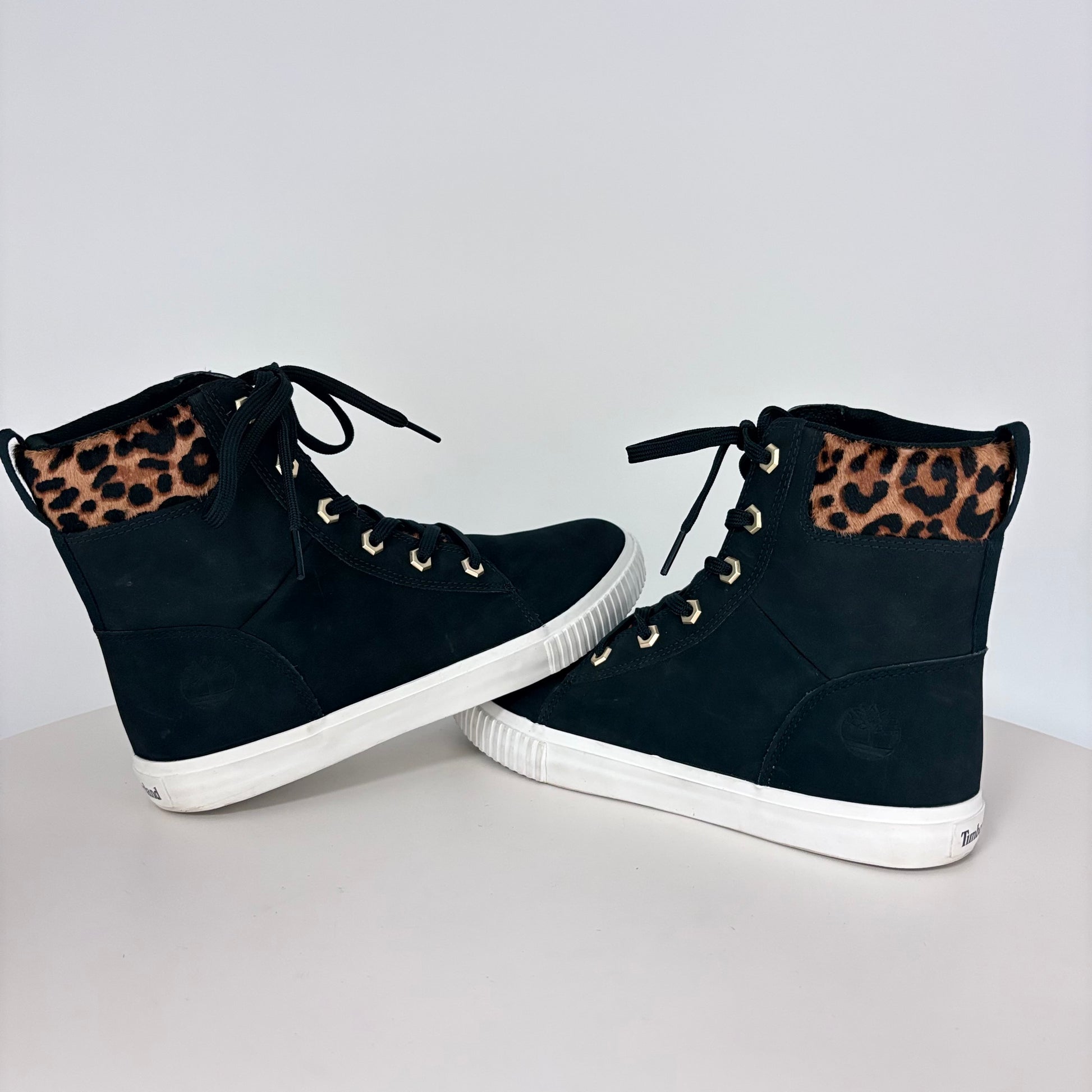 Black high-top sneakers with leopard print accents on a light gray background