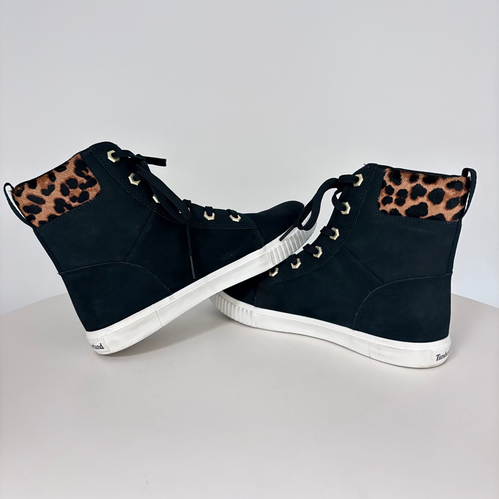Black high-top sneakers with leopard print accents on a white background