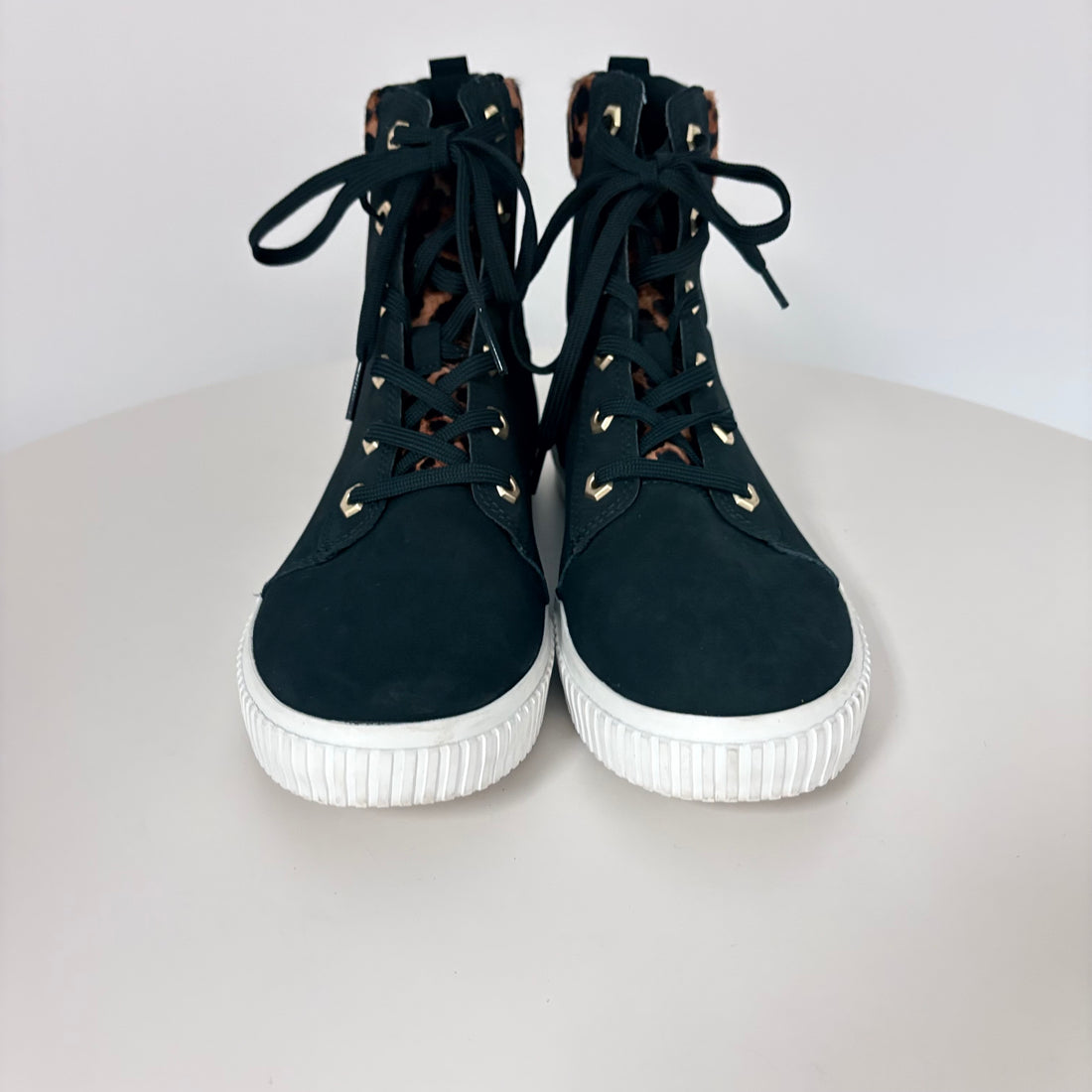 Black high-top sneakers with white soles on a light gray background