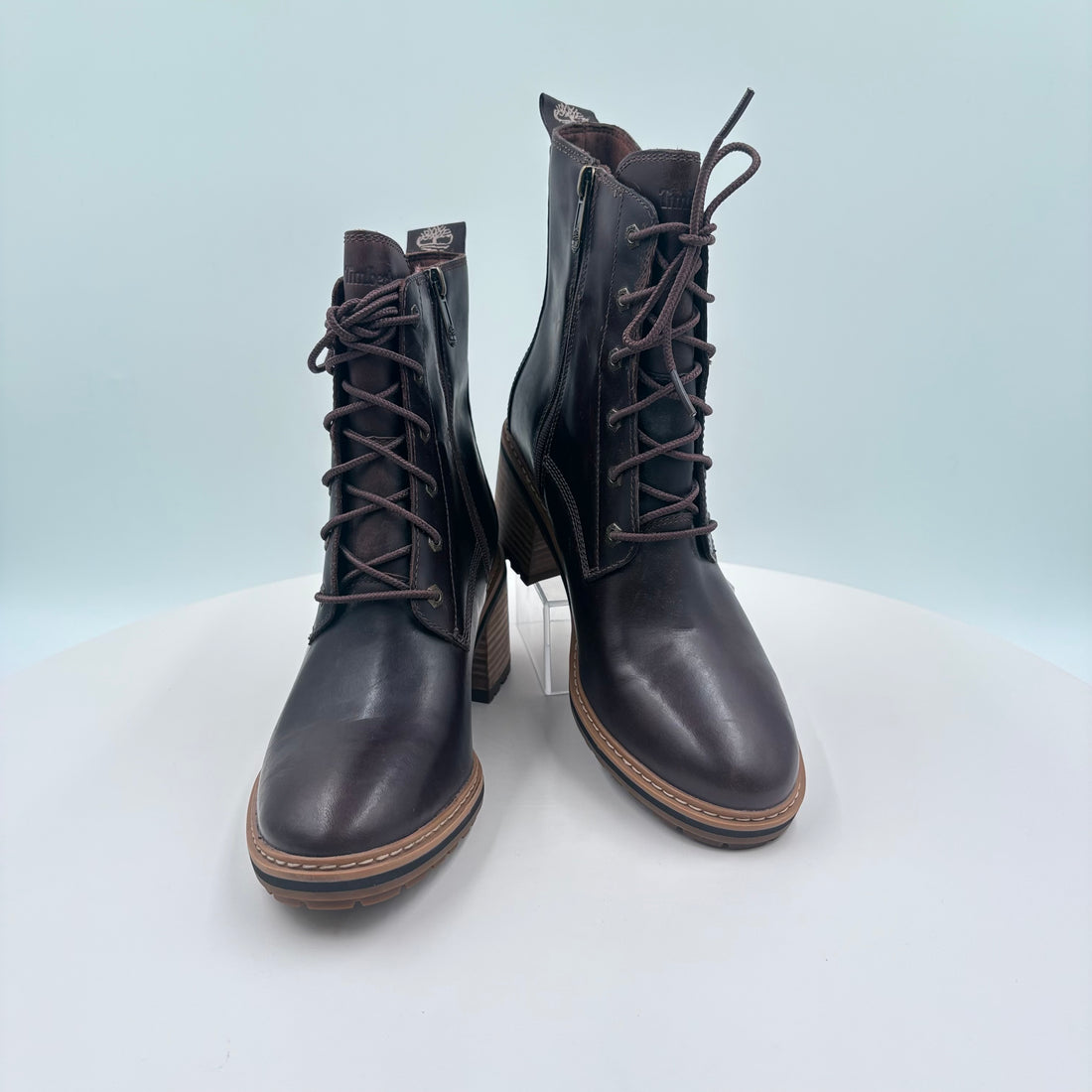 Pair of black leather boots with laces on a light gray background