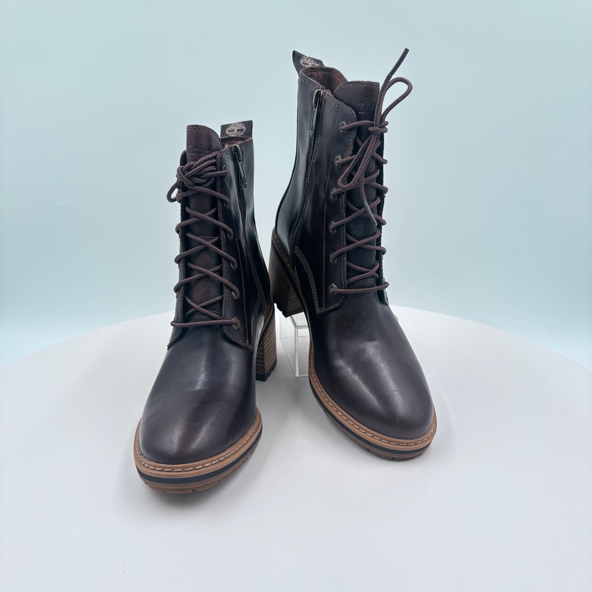Pair of black leather boots with laces on a light gray background