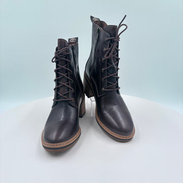 Pair of black leather boots with laces on a light gray background