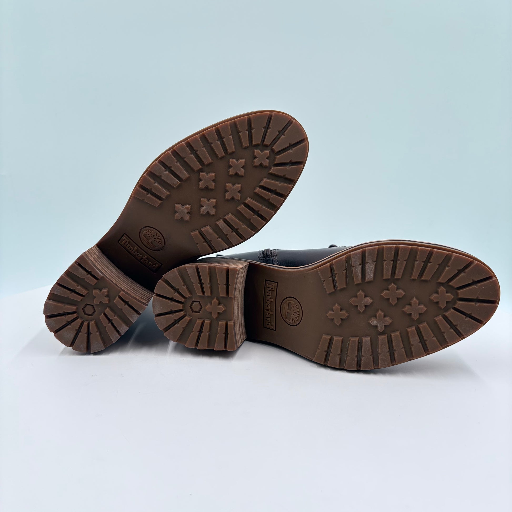 Brown leather shoes with tread pattern on sole against a light gray background