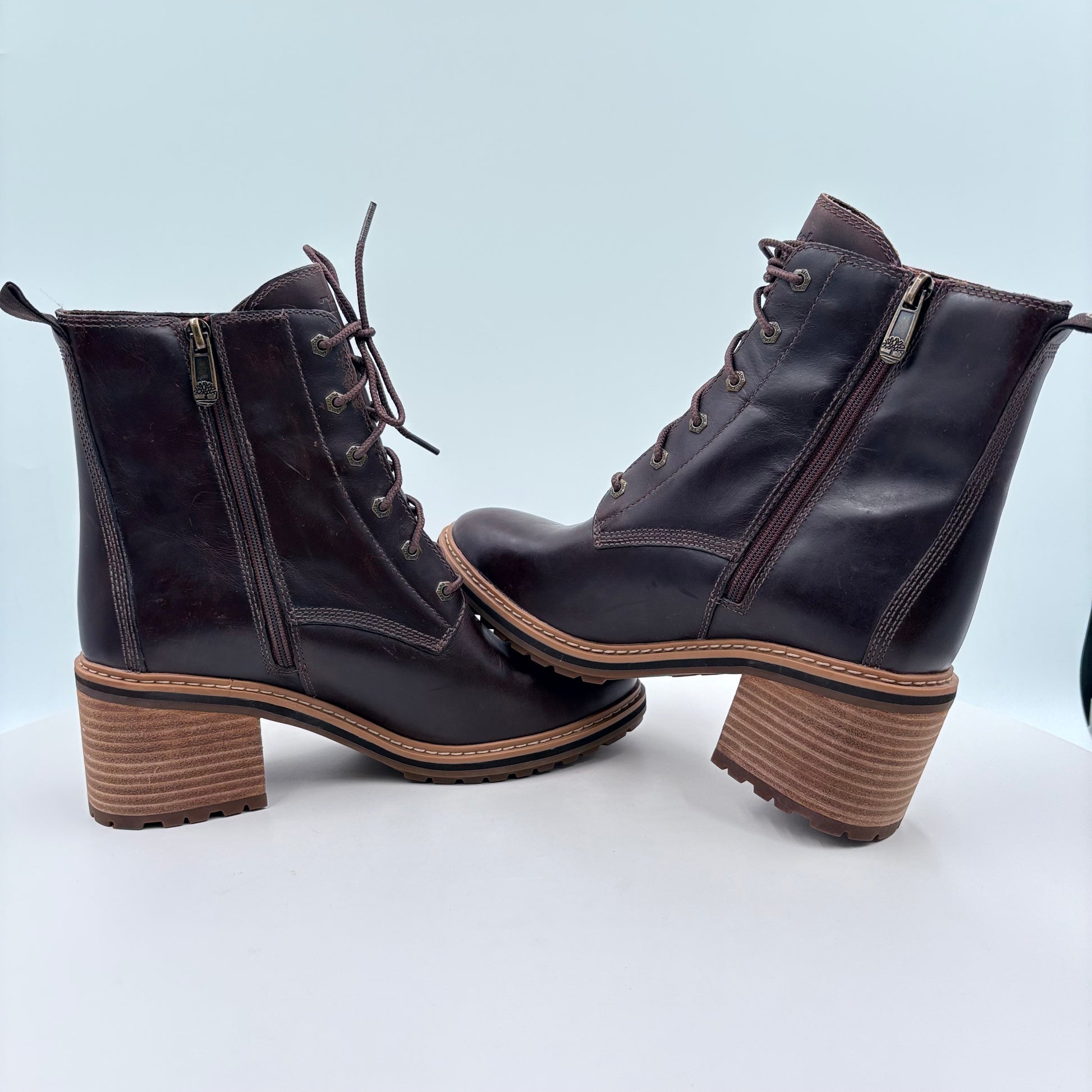 Pair of black leather boots with brown soles on a light blue background