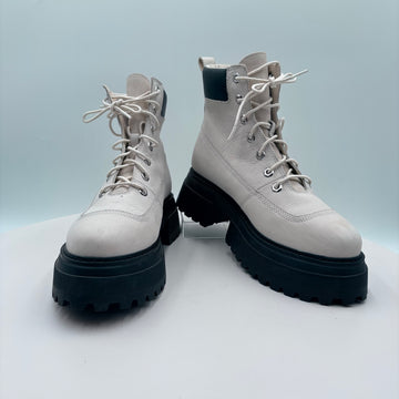 Pair of white boots with black soles on a light gray background